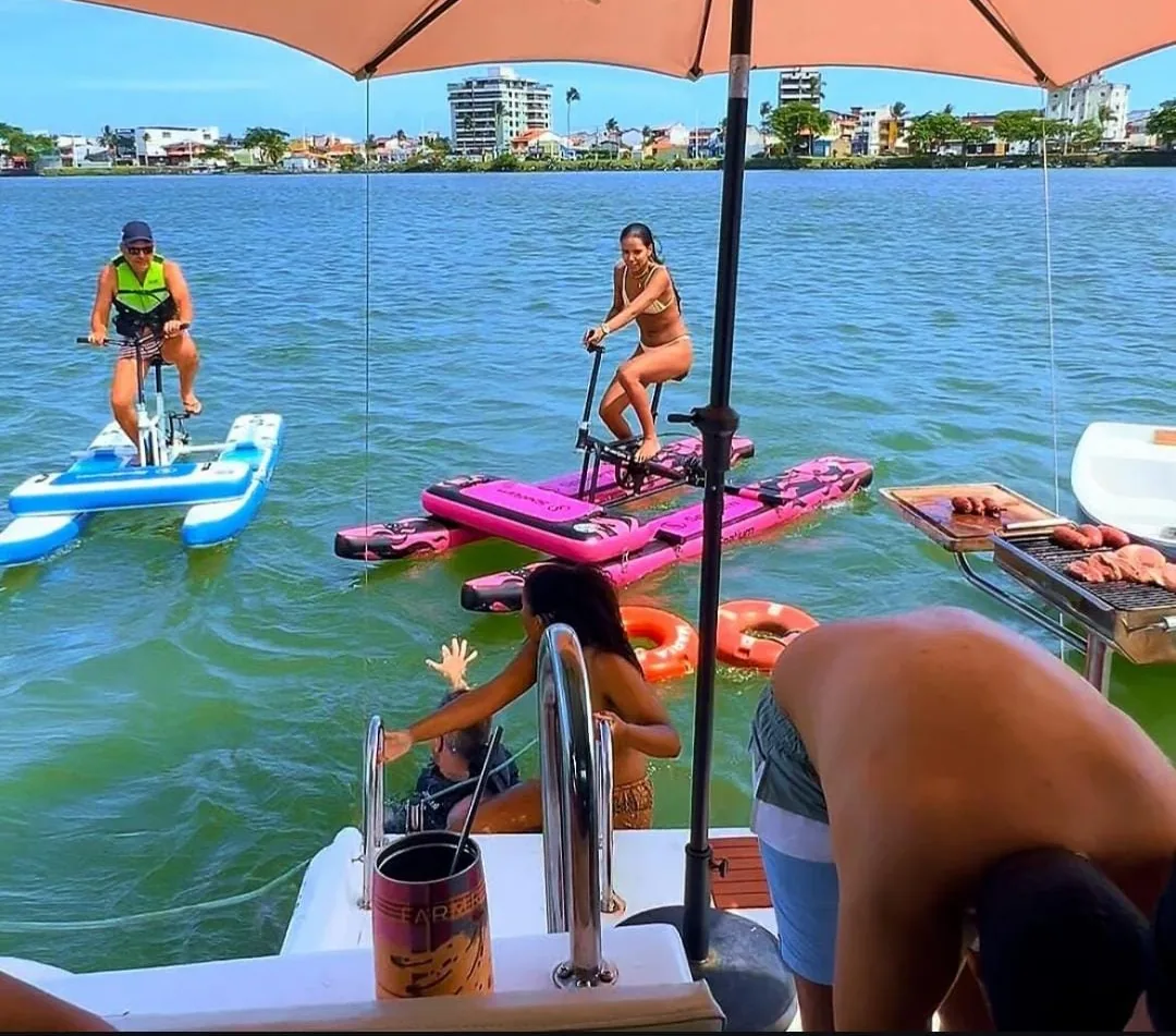 Convidados usando bicicletas aquáticas ao lado do barco