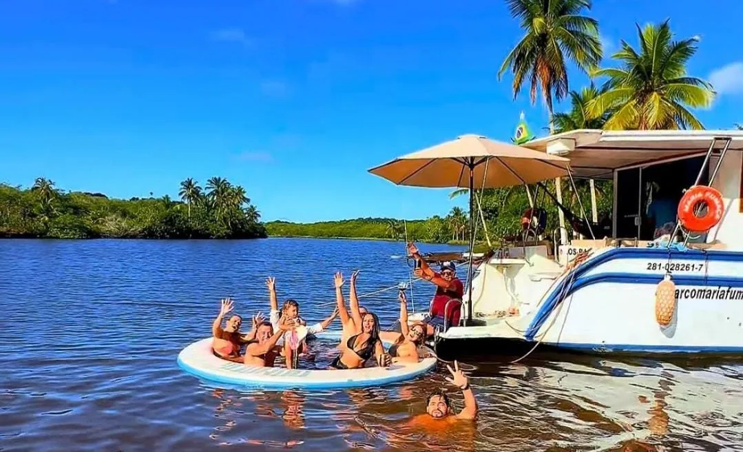 Grupo acenando em uma boia ao lado do barco Maria Fumaça